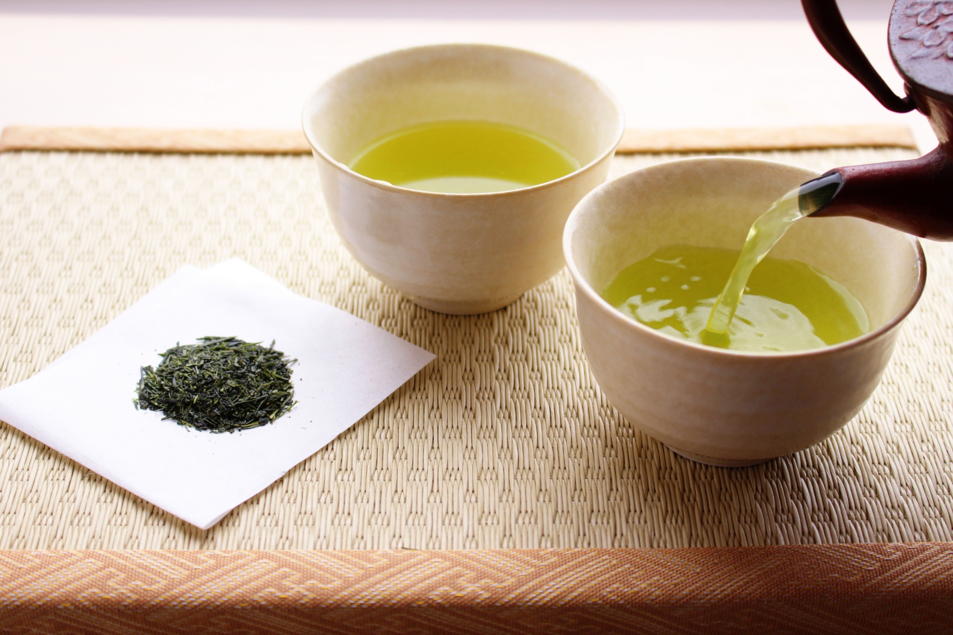 畳の上に置かれた一杯のお茶と急須で湯吞みにお茶を注ぐ様子